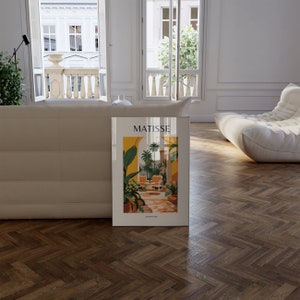 May include: A white framed poster with a colorful illustration of a tropical courtyard with the text "MATISSE ART PRINTS" at the bottom.