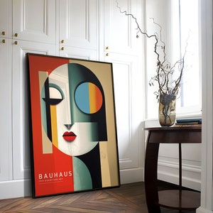 Puede incluir: Un p&oacute;ster enmarcado con un dise&ntilde;o abstracto geom&eacute;trico en rojo, azul, amarillo y negro. El p&oacute;ster presenta una cara estilizada y el texto "Bauhaus 1919 Exhibition Art".