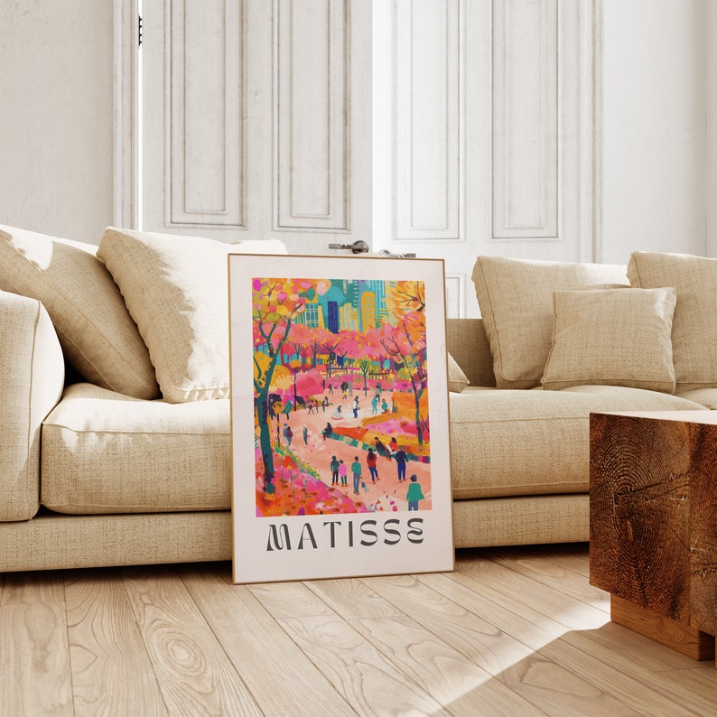 May include: A framed art print depicting a park scene with figures, trees, and buildings in bright colours. The artwork uses pink, orange, and blue tones. The print is labelled "MATISSE" in a bold, sans-serif font.