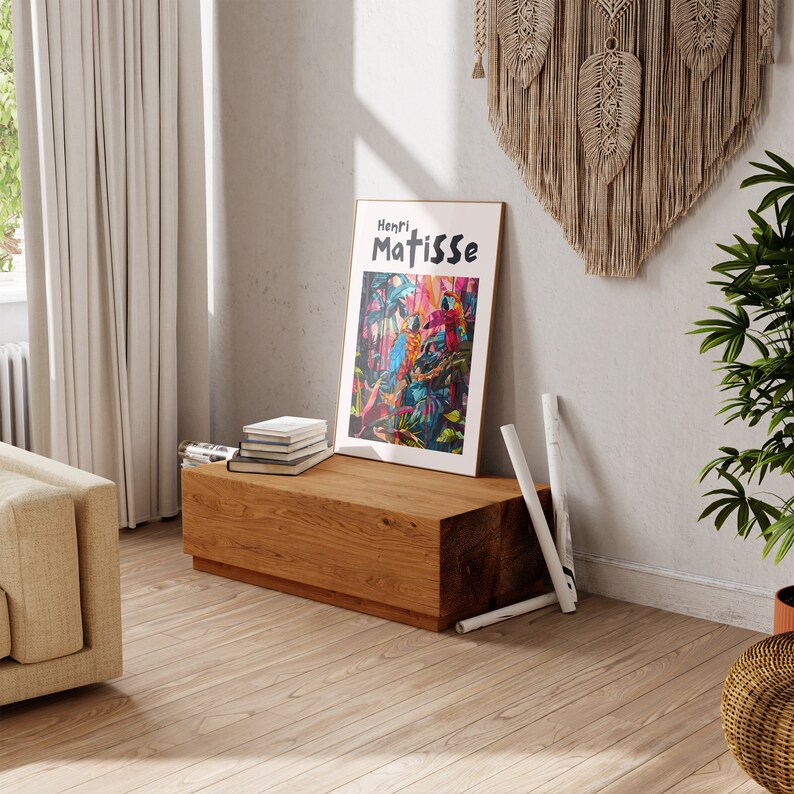 May include: A wooden bench with a framed print of a colorful painting featuring birds and foliage. The print has the text "Henri Matisse" at the top. The bench is in a room with a white wall and a macrame wall hanging.