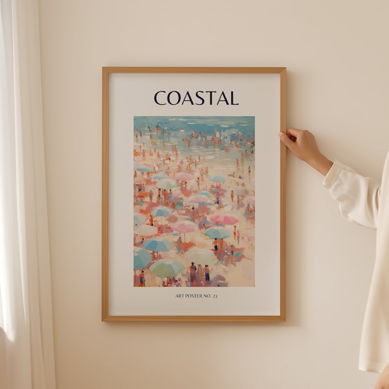 K&ouml;nnte beinhalten: Ein gerahmter Kunstdruck mit dem Titel "COASTAL" zeigt eine Strandszene mit zahlreichen Menschen und bunten Sonnenschirmen. Das Kunstwerk verwendet eine helle Farbpalette mit Blau-, Rosa- und Beiget&ouml;nen. Der Text "ART POSTER NO. 23" befindet sich unten.