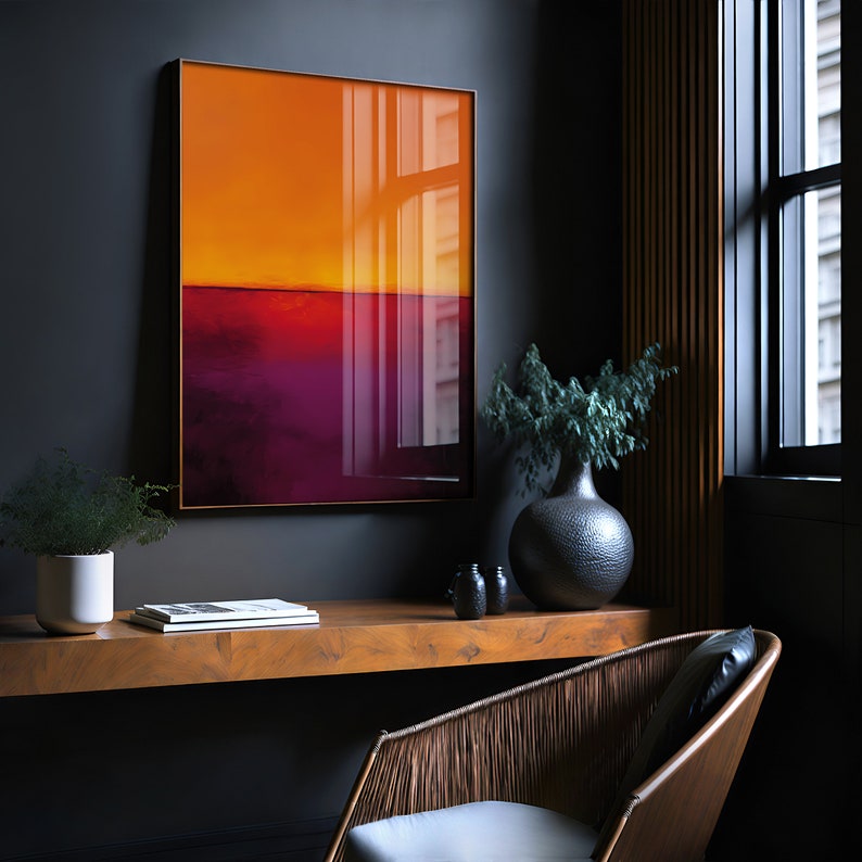 May include: A framed abstract art print with a gradient of orange and purple hues. The artwork hangs on a dark gray wall above a wooden desk. A decorative vase and chair are also visible in the room.