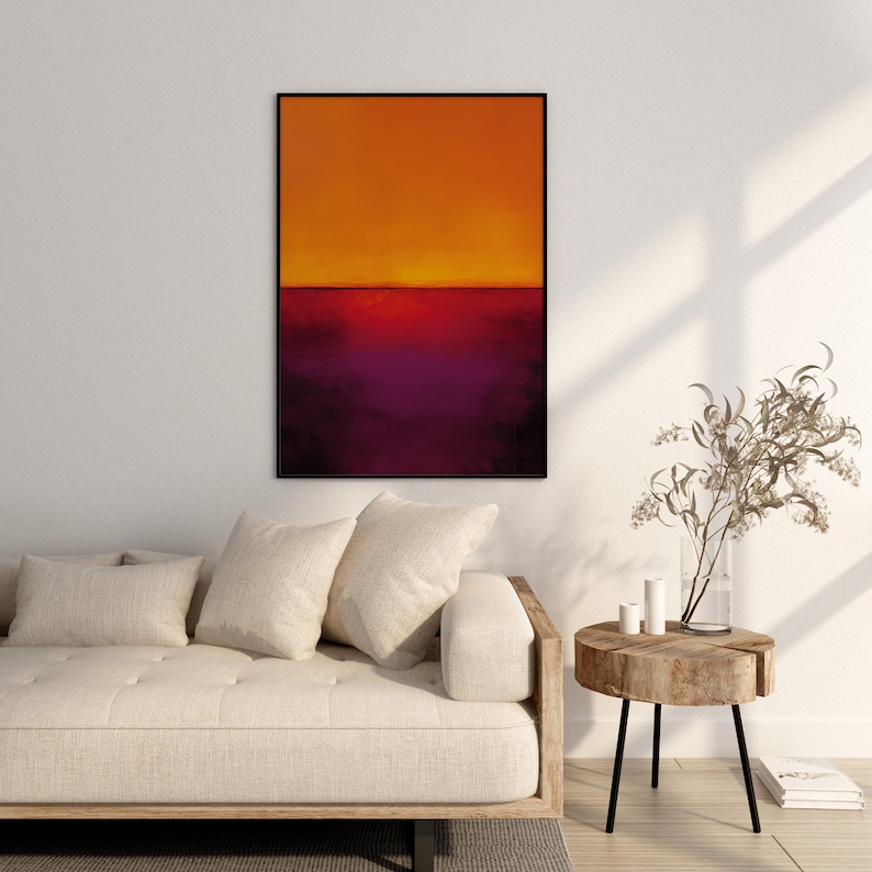 May include: Abstract art print in a black frame. The artwork features a gradient of colors, with orange at the top transitioning to deep purple at the bottom. The painting is displayed above a beige sofa and a wooden side table.