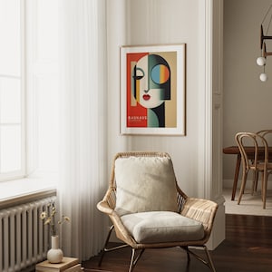 Puede incluir: Un p&oacute;ster enmarcado con un dise&ntilde;o geom&eacute;trico de la cara de una mujer en tonos rojos, verdes, azules y amarillos. El p&oacute;ster se titula "Bauhaus" y est&aacute; colgado en una pared blanca.