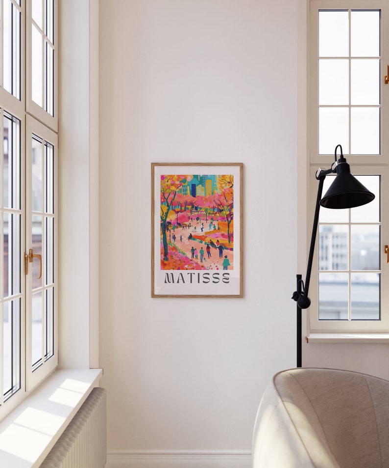 May include: A framed art print depicting a lively street scene with figures and trees. The artwork uses a bright palette of pink, orange, and blue. The word "MATISSE" is printed in a bold, sans-serif font at the bottom of the print.