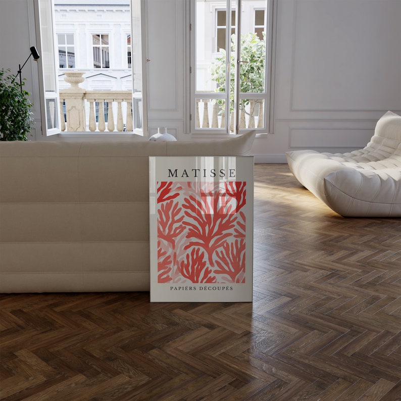 Op de afbeelding: Een ingelijste print van een Matisse-kunstwerk met een rood koraalontwerp met de tekst "MATISSE PAPIERS DECOUPES".