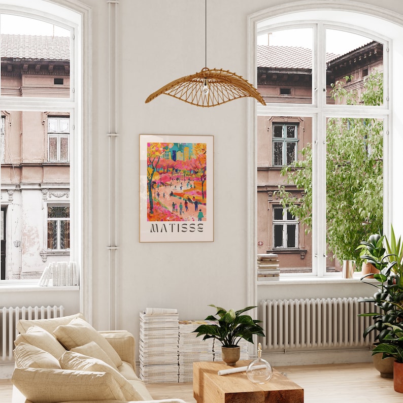 May include: A living room featuring a framed Matisse art print. The print depicts a vibrant street scene with figures. A woven pendant light hangs above a wooden coffee table. The room has large windows and indoor plants.
