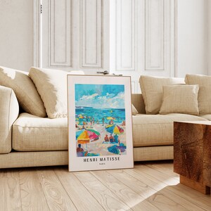 May include: A framed print of a painting by Henri Matisse depicting a beach scene with colorful umbrellas and people enjoying the sun and sea. The text "HENRI MATISSE PARIS" is at the bottom of the print.