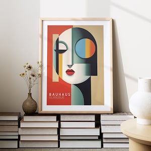 Puede incluir: Un p&oacute;ster enmarcado con un dise&ntilde;o abstracto geom&eacute;trico en tonos de rojo, amarillo, azul, verde y negro. El p&oacute;ster presenta una cara estilizada con una boca roja y un ojo azul. El texto "BAUHAUS 1919 EXHIBITION ART" est&aacute; impreso en la parte inferior del p&oacute;ster.