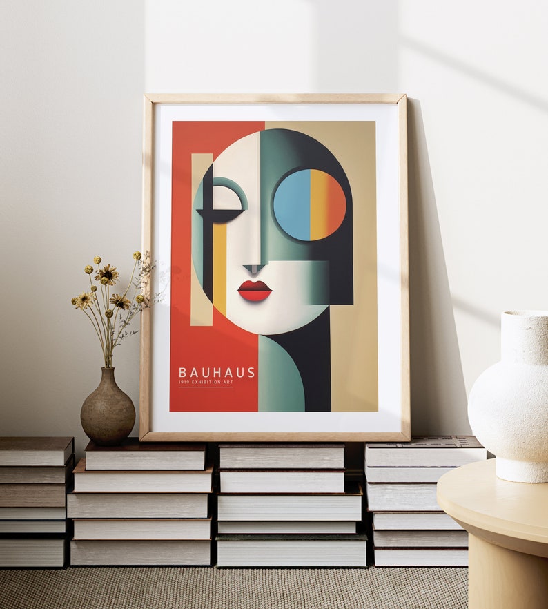Puede incluir: Un p&oacute;ster enmarcado con un dise&ntilde;o abstracto geom&eacute;trico en tonos de rojo, amarillo, azul, verde y negro. El p&oacute;ster presenta una cara estilizada con una boca roja y un ojo azul. El texto "BAUHAUS 1919 EXHIBITION ART" est&aacute; impreso en la parte inferior del p&oacute;ster.