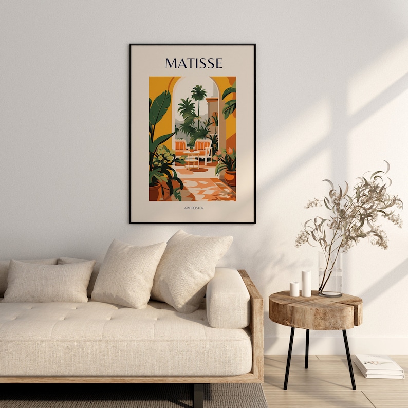 May include: A black framed art print with the text "MATISSE" in yellow letters. The print features a colorful illustration of a patio with a view of palm trees and a tiled floor. The text "ART POSTER" is at the bottom of the print.