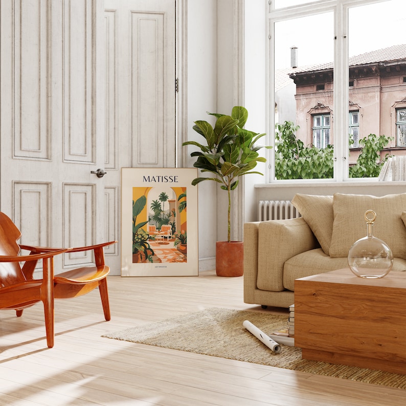 May include: A living room interior with a brown leather armchair, a beige sofa, a wooden coffee table, a potted ficus plant, and a poster with the text "MATISSE" on the wall.