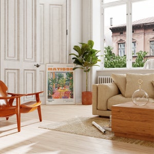 May include: A living room interior with a brown leather armchair, a beige sofa, a wooden coffee table, a potted ficus plant, and a poster of a Matisse painting titled "Garden Nice, France".
