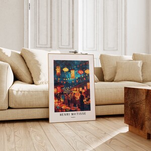 May include: A framed print of a painting depicting a night market scene with colourful lanterns and people walking through the market. The artist's name, Henri Matisse, and the city, Paris, are printed at the bottom of the print.