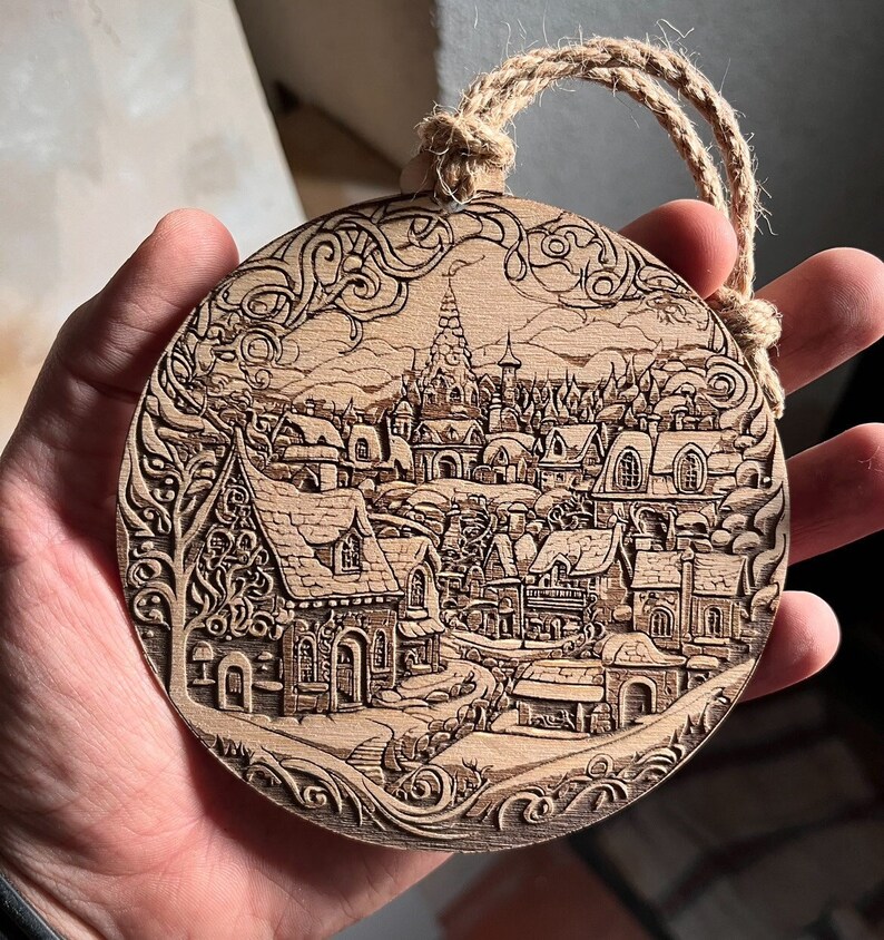 May include: A round wooden ornament with a detailed carving of a whimsical village scene. The ornament features intricate details of houses, trees, and a winding path. The carving is done in a light brown color, giving it a rustic and charming look.
