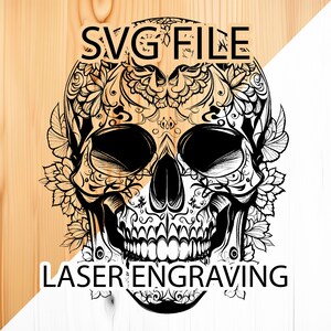 May include: Black and white illustration of a sugar skull with intricate floral designs. The skull is surrounded by leaves and flowers. The text "SVG FILE LASER ENGRAVING" is visible at the top and bottom of the image.