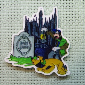 May include: A cartoon image of Goofy and Pluto in front of a haunted house. Goofy is holding a lantern and Pluto is running towards a tombstone that reads "The Haunted Mansion".