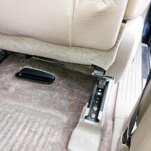Puede incluir: Primer plano del interior de un coche que muestra la alfombra gris y la hebilla del cintur&oacute;n de seguridad negro. El asiento est&aacute; plegado y el cintur&oacute;n de seguridad est&aacute; asegurado.