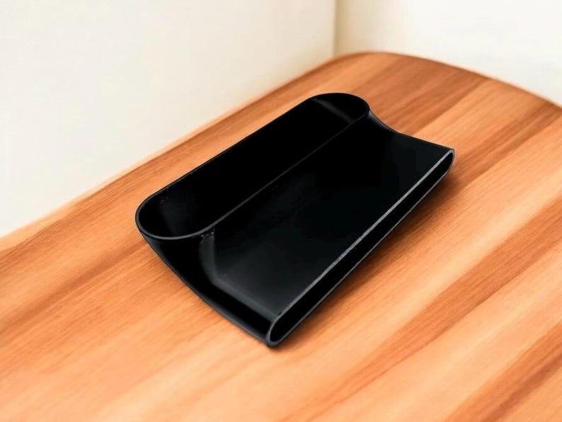 Puede incluir: Un organizador de pl&aacute;stico negro con dos compartimentos. El organizador est&aacute; dise&ntilde;ado para guardar objetos como bol&iacute;grafos, l&aacute;pices u otros objetos peque&ntilde;os.