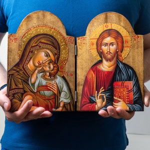 Groot houten tweeluik met de iconen van Jezus Christus en de heilige Theotokos op een bruine achtergrond met een Griekse schat als achtergrond voor inspirerende woondecoraties.
