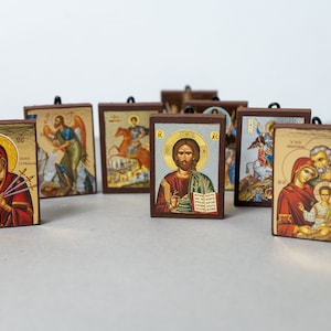 Pode incluir: Uma cole&ccedil;&atilde;o de 10 pequenos &iacute;cones religiosos emoldurados com v&aacute;rias imagens de santos e figuras religiosas. Os &iacute;cones s&atilde;o pintados em um estilo tradicional com detalhes dourados e s&atilde;o exibidos em uma superf&iacute;cie branca.