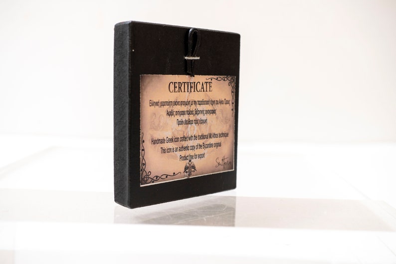 May include: A black wooden frame with a certificate of authenticity for a handmade Greek icon. The certificate is printed on parchment paper with a decorative border and includes the text "&Epsilon;&lambda;&lambda;&eta;&nu;&iota;&kappa;ή &chi;&epsilon;&iota;&rho;&omicron;&pi;&omicron;ί&eta;&tau;&eta; &epsilon;&iota;&kappa;ό&nu;&alpha; &mu;&iota;&mu;έ&nu;&eta; &mu;&epsilon; &tau;&eta; &pi;&rho;&omicron;ϊ&sigma;&tau;&omicron;ή έ&chi;&eta; &tau;&iota; &kappa;&alpha;&iota; &tau;&alpha;&sigmaf;" and "This icon is an authentic copy of the Byzantine original".