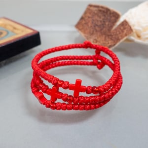 Peut inclure: Un bracelet de prière rouge avec trois brins de cordon noué et des perles en forme de croix rouges.