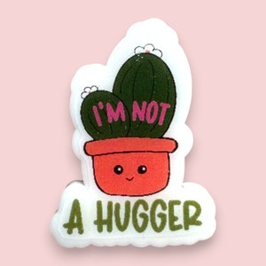 May include: A white sticker featuring a green cactus in a red pot. The cactus has pink flowers and the text "I'M NOT A HUGGER" in green lettering.