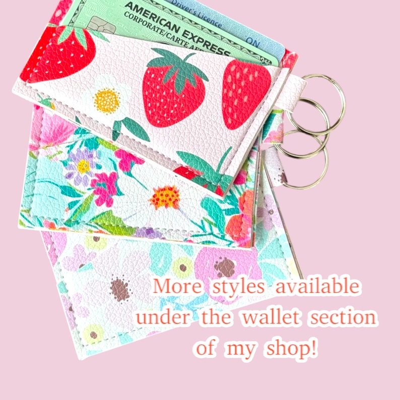 May include: Three colourful fabric card holders with a key ring attached. The card holders feature floral and strawberry patterns. The text "More styles available under the wallet section of my shop!" is visible at the bottom of the image.