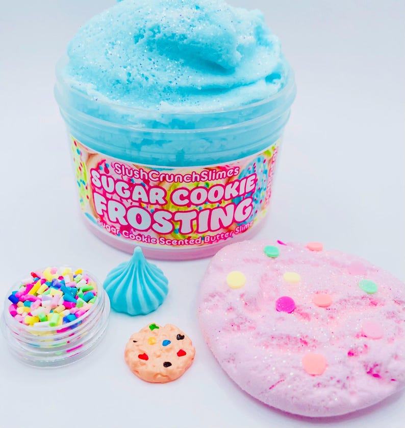 May include: A jar of blue, sparkly slime labeled "Sugar Cookie Frosting" with a variety of colorful sprinkles and miniature cookie-shaped decorations. A pink, glittery slime with colorful sprinkles is also present.