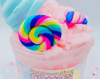 Könnte beinhalten: Ein Behälter mit rosa, nach Zuckerwatte duftendem Schleim, verziert mit blauen und bunten Dekorationen. Der Behälter trägt die Aufschrift "SlushCrunchSlimes Cotton Candy".
