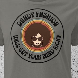 Può includere: Maglietta grigia con una grafica retrò di una donna con capelli afro che indossa occhiali da sole. La grafica è circondata da un cerchio con il testo "Dandy Fashion Will Get Your Mind Right".