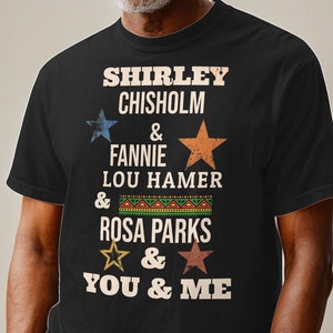 May include: Black t-shirt with a vintage-style graphic featuring the names Shirley Chisholm, Fannie Lou Hamer, Rosa Parks, and the text "You & Me".