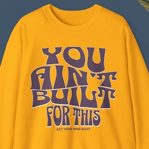 May include: Yellow sweatshirt with a purple graphic that says "You ain't built for this" and "Get your mind right".