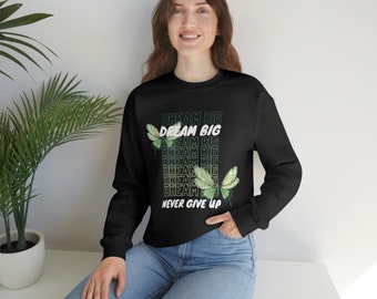 Könnte beinhalten: Schwarzer Pullover mit einem grafischen Druck von Schmetterlingen und dem Text "DREAM BIG", der mehrmals wiederholt wird. Der Text "NEVER GIVE UP" ist unter den Schmetterlingen gedruckt.