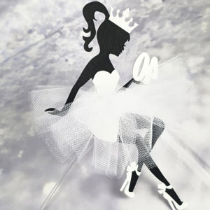 Könnte beinhalten: Schwarze Silhouette einer Ballerina, die eine Krone und einen weißen Tüllrock trägt. Die Ballerina hält eine weiße Nummer eins.