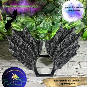 May include: Black dragon wings bookend, a 3D printed design, with the text "Bookstand Drachenflügel" and "Super für Bücher und Ebooks."  The bookend is on a white brick background with green foliage.