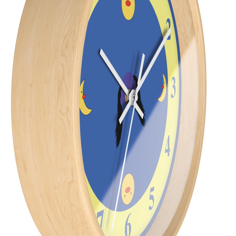 Puede incluir: Un reloj con marco de madera, con una esfera azul y n&uacute;meros amarillos. El reloj tiene una aguja de minutos blanca y una aguja de horas negra. Hay tres lunas amarillas con caras rojas en la esfera del reloj.