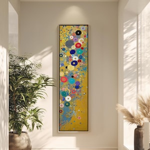 Puede incluir: Una pintura abstracta vertical con fondo amarillo y círculos coloridos. Los círculos son en tonos de azul, rojo, blanco y amarillo. La pintura está enmarcada en negro y cuelga de una pared blanca.