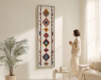 Może przedstawiać: Długi, prostokątny obraz ścienny z kremowym tłem i geometrycznym wzorem w odcieniach czerwieni, niebieskiego, żółtego i brązu. Wzór przedstawia kształty rombów i gwiazd. Grafika jest oprawiona w jasne drewno.