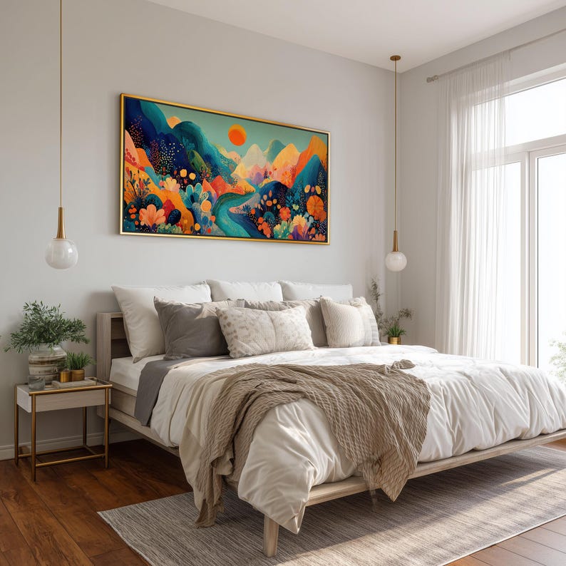 May include: A bedroom scene featuring a large, framed landscape painting with a gold frame above a bed. The painting depicts a colorful mountain scene with a bright orange sun. The bed has white bedding, gray pillows, and a beige throw blanket.
