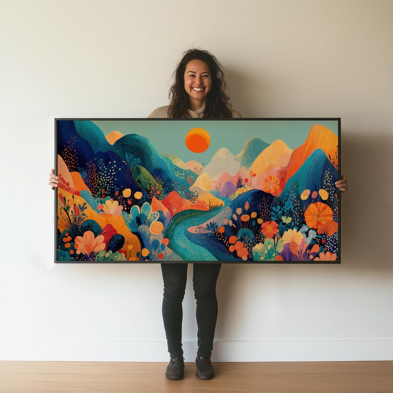 May include: A framed art print featuring a colorful landscape with mountains, a river, and a bright orange sun. The artwork uses a vibrant palette of blues, oranges, and greens, creating a cheerful and inviting scene. The frame is black.