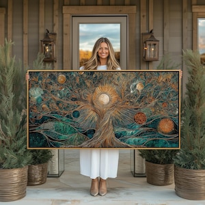 Può includere: Un'opera d'arte incorniciata con una cornice dorata, raffigurante un albero stilizzato con un design di sole e luna. L'opera d'arte utilizza una tavolozza di colori turchese, marrone e oro. I rami e le foglie dell'albero sono finemente dettagliati, con corpi celesti sparsi.