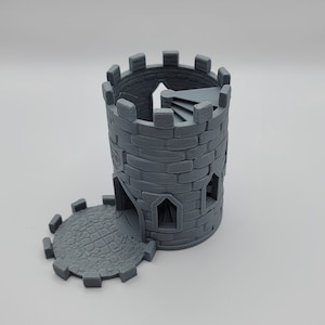 May include: A gray 3D printed tower shaped dice rolling tower with a spiral staircase inside. The tower has a removable base with a stone-like texture.