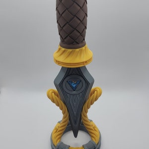 May include: A 3D printed dagger with a brown braided handle, a gray blade with a blue and silver eye design, and a yellow rope-like base.