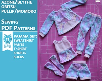 Könnte beinhalten: Ein Set Puppenkleidung für eine Puppe wie Blythe, Obitsu oder Pullip. Das Set beinhaltet einen Pullover, eine Hose, ein T-Shirt, Shorts und Socken. Die Kleidung ist alle mit einem pastellblauen, rosa und weißen Wolkenmuster bedruckt. Die Kleidung liegt auf einer rosa Schneidematte mit einem Lineal.