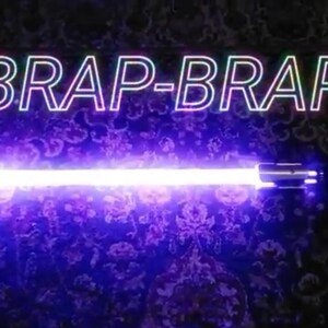 May include: A purple lightsaber with the words "BRAP-BRAP" in white outlined text above it.
