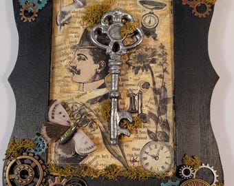May include: A steampunk-themed wall art piece. It features a black, ornate frame adorned with gears, moss, and a vintage key. Inside, a collage includes a vintage illustration, a butterfly, and clock faces.