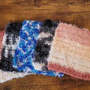 Puede incluir: Cuatro paños de cocina de ganchillo en diferentes colores: rosa, negro, azul y blanco. Los paños de cocina están hechos con un hilo esponjoso y tienen una superficie texturizada.