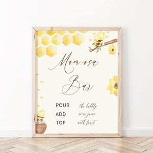 May include: A printable sign for a "Mimosas Bar" with a bee and honeycomb design. The sign says "Pour the bubbly, add some juice, top with fruit".